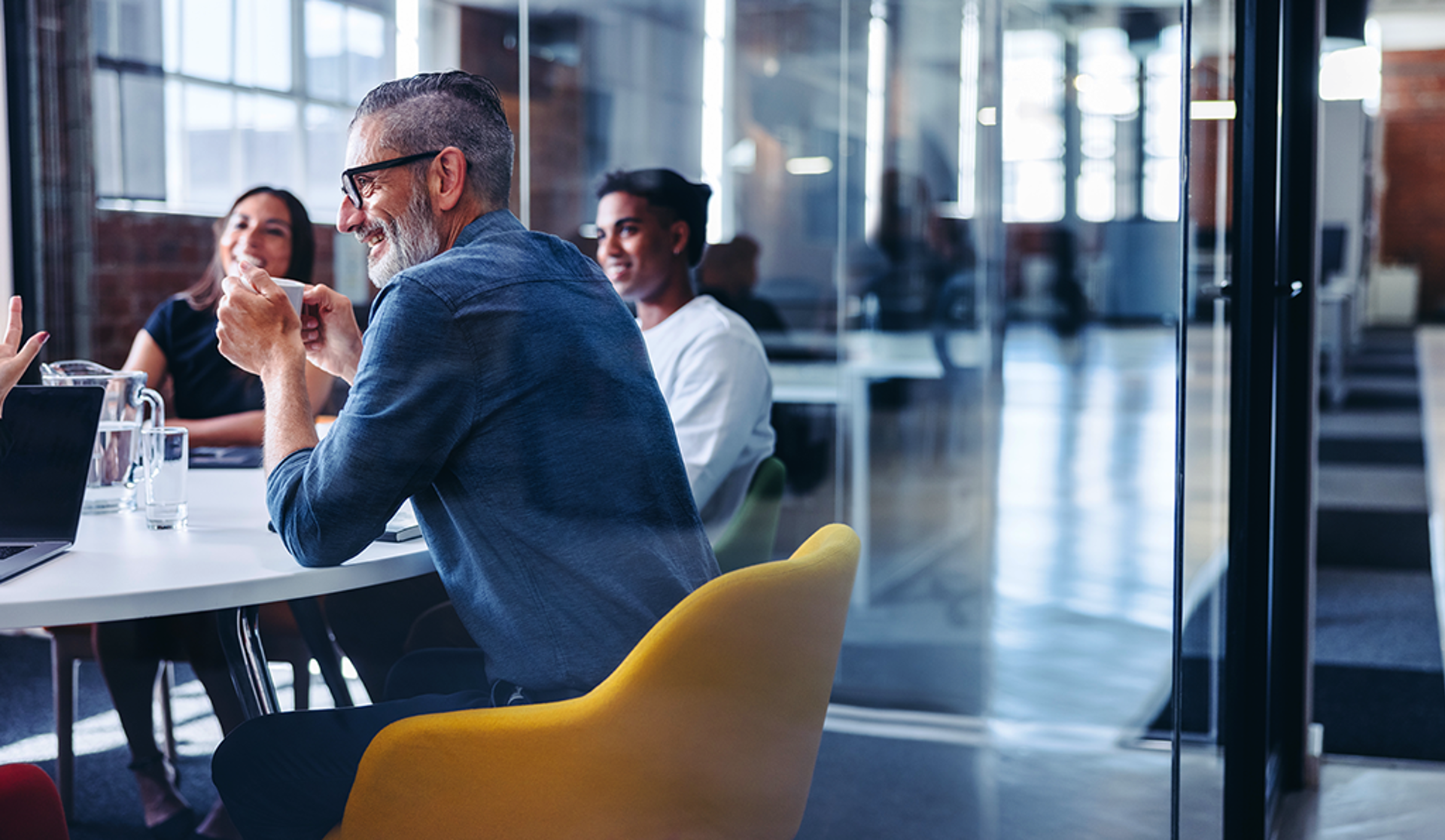 A team of people seated at a table in an office, actively participating in a meeting or brainstorming session.